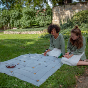 Zwei Frauen sitzen vor einem ausgebreiteten Spiel auf der Wiese