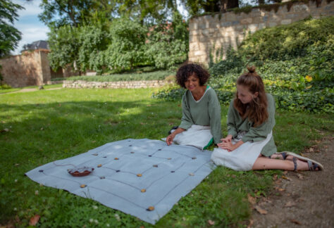 Zwei Frauen sitzen vor einem ausgebreiteten Spiel auf der Wiese